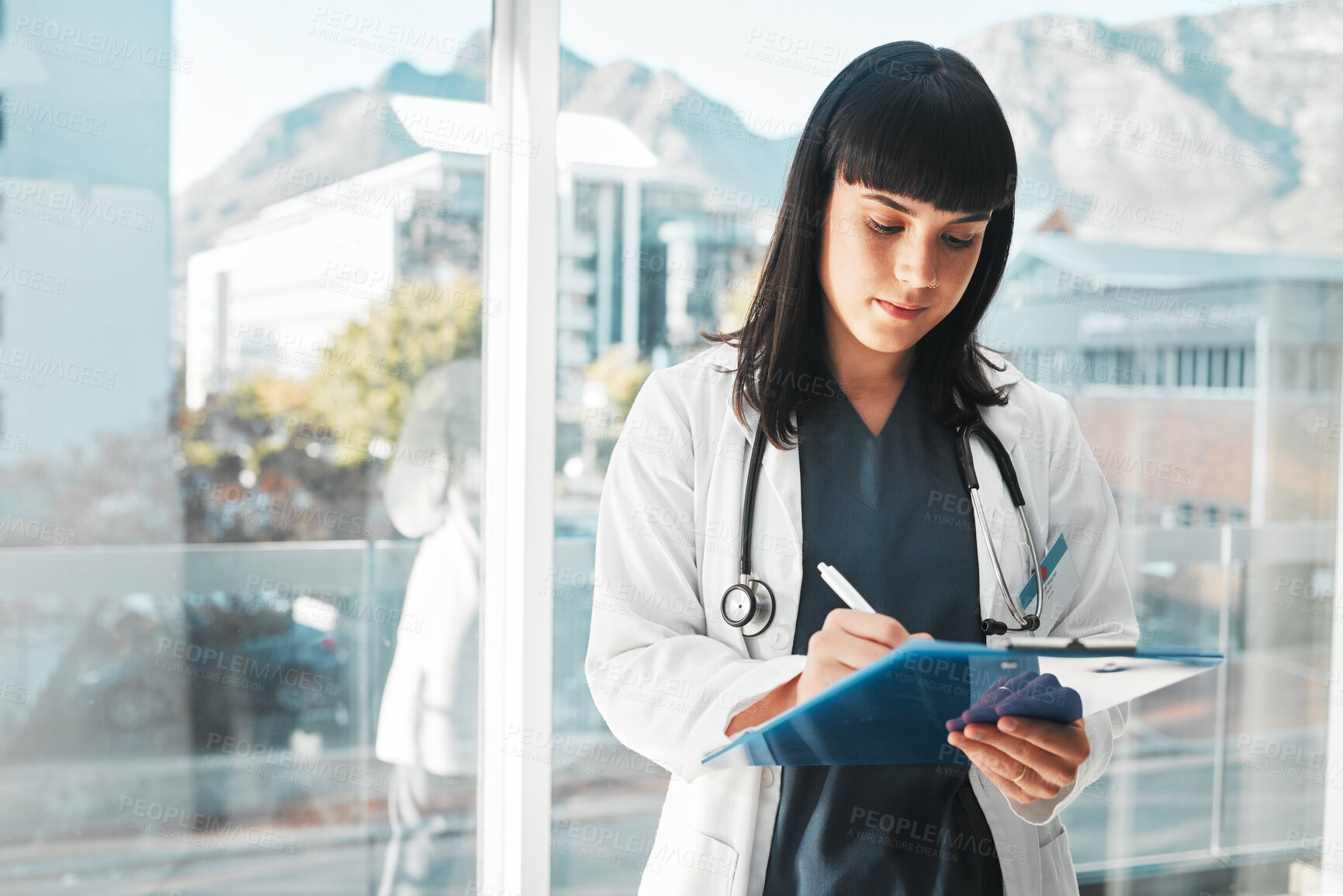Buy stock photo Woman, doctor and writing on clipboard by window for healthcare planning, strategy or notes at hospital. Female medical expert with paperwork, prescription or write for medicare details at clinic