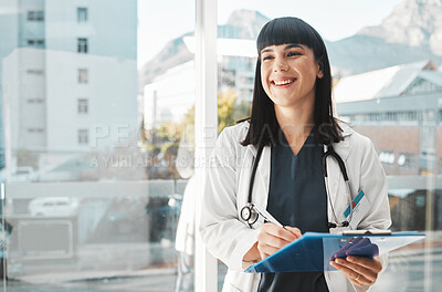 Buy stock photo Woman, doctor and smile writing on clipboard by window for healthcare planning, strategy or notes. Happy female medical expert smiling with paperwork, prescription or medicare details at hospital