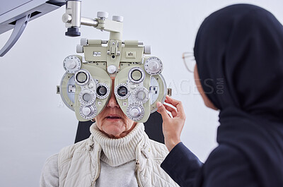 Buy stock photo Eye exam, vision and senior woman with optometrist in clinic for testing eyes, check eyesight and optical care. Optometry, healthcare and Muslim optician with patient, phoropter and medical tools