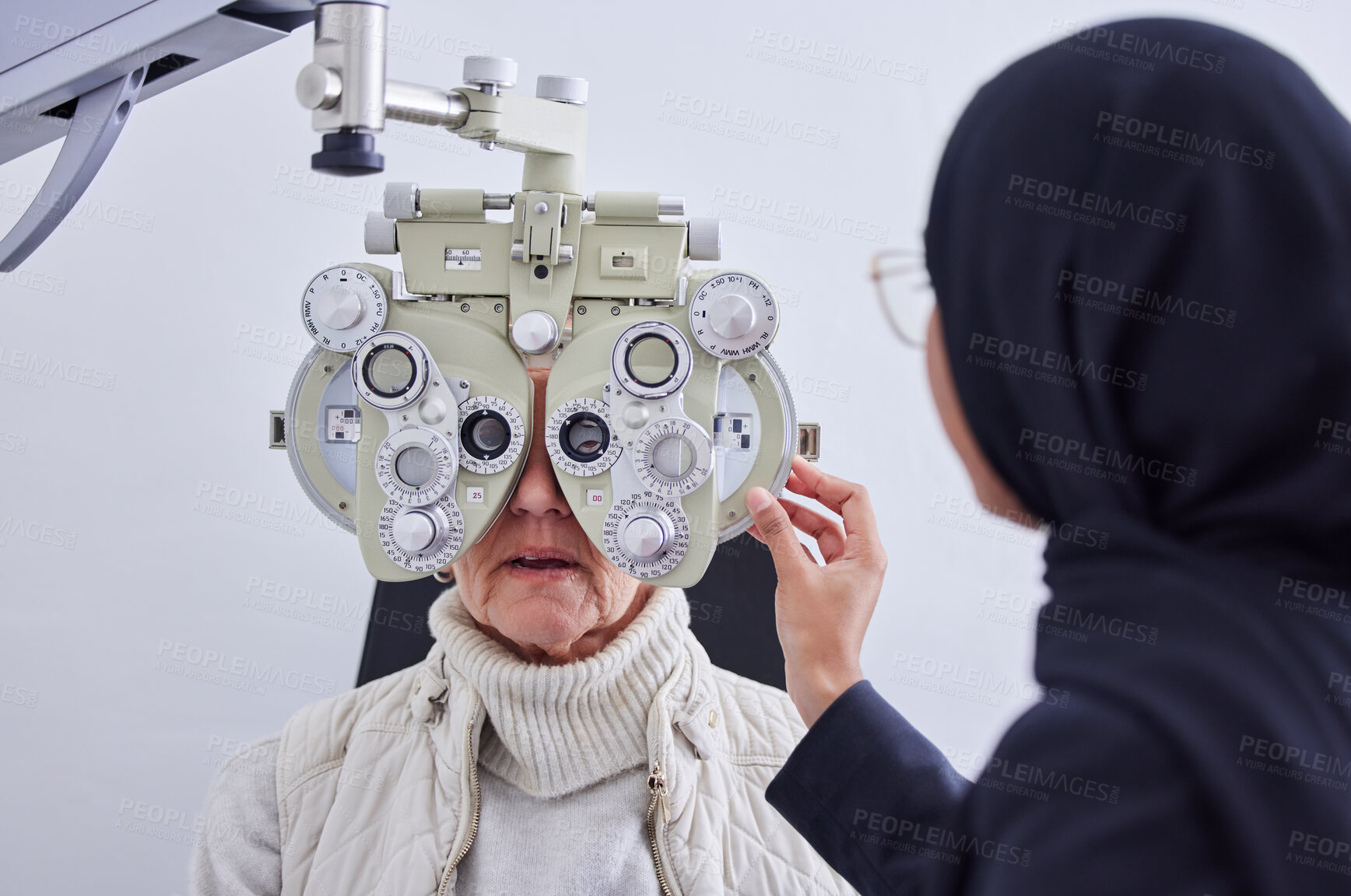 Buy stock photo Eye exam, vision and senior woman with optometrist in clinic for testing eyes, check eyesight and optical care. Optometry, healthcare and Muslim optician with patient, phoropter and medical tools