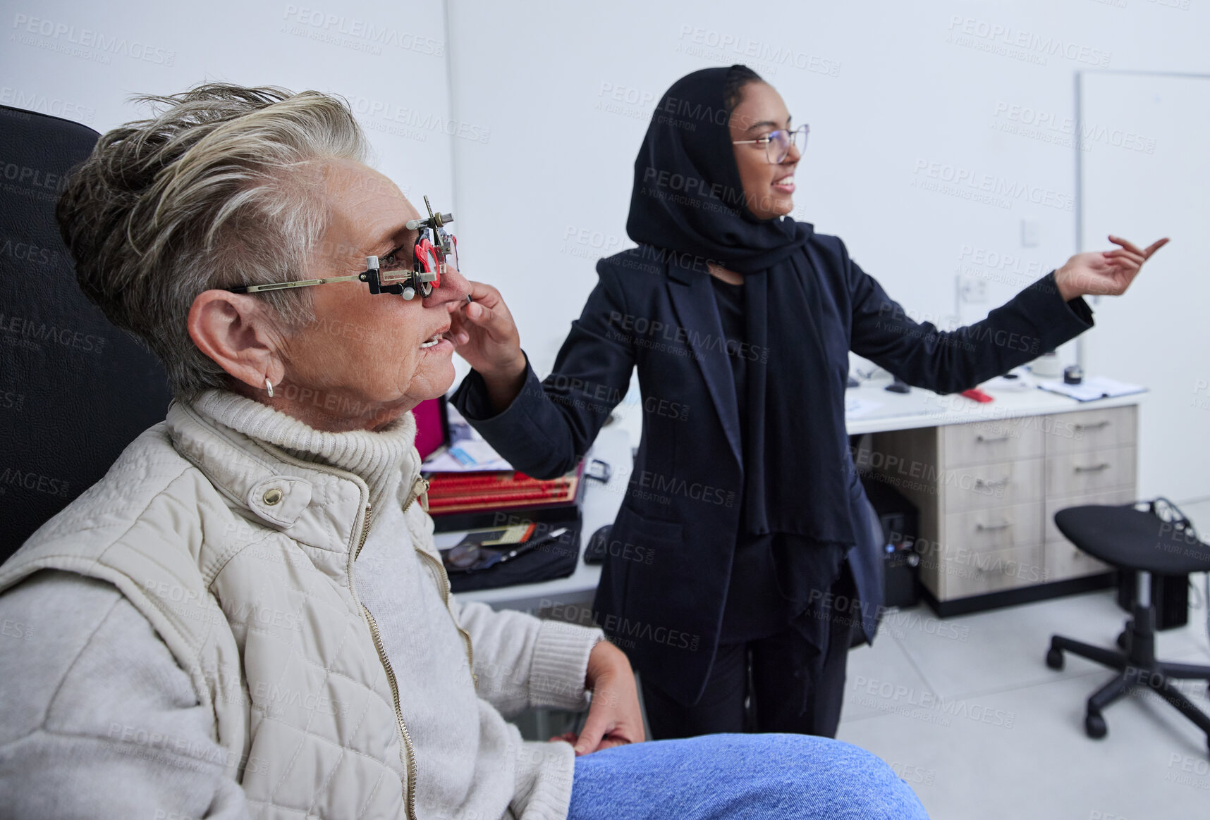 Buy stock photo Eye exam, frame and woman reading with optometrist in clinic for vision test, eyesight and optical assessment. Optometry, healthcare and Muslim optician with patient in glasses, lens and medical tool