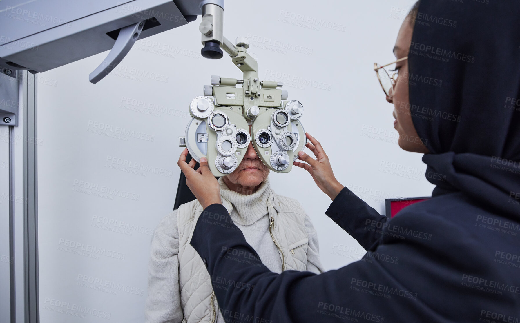 Buy stock photo Eye exam, optometry consultation and woman test for medical, healthcare and vision with muslim expert. Eyes check or consulting of senior person and professional optometrist with phoropter machine