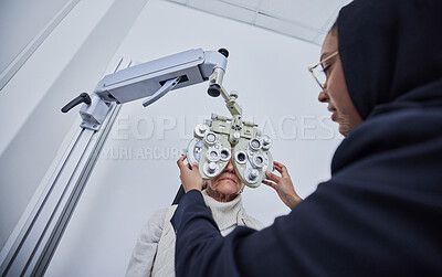 Buy stock photo Vision exam, eyes and senior woman with optometrist in clinic for test, eyesight and optical assessment. Optometry, healthcare and Muslim optician with patient for phoropter, lens and medical machine