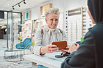 Eye care, senior woman and glasses for patient shopping for vision lens or frame at optics store. Happy customer person talking to service consultant for decision on optometry case choice for eyes