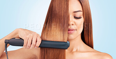 Buy stock photo Face, beauty and woman with hair straightener in studio isolated on a blue background. Haircare, wellness and young female model with flat iron for salon treatment hairstyle, aesthetic or balayage.