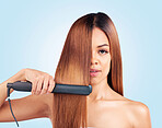 Face portrait, beauty and woman with hair straightener in studio isolated on a blue background. Haircare, product and female model with flat iron for salon treatment, hairstyle aesthetic or balayage.
