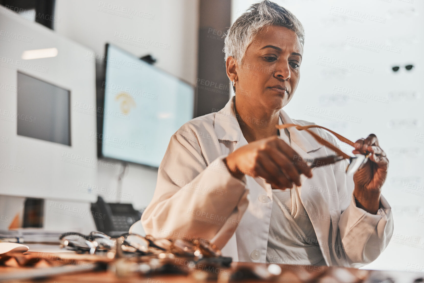 Buy stock photo Elderly optometrist woman, glasses and design for focus, vision or frame planning at desk in clinic. Senior optician, spectacle designer and eye care in workplace for fashion, small business and goal