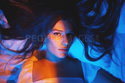 Buy stock photo Portrait, vaporwave lights and young woman face in bedroom with creative disco lighting. Makeup, beauty and model resting and feeling relax and calm on a bed pillow with cyberpunk aesthetic 