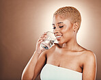 Drinking water, black woman and glass for health on a brown background for skincare or diet. Aesthetic model person smile for clean and sustainable liquid for healthy lifestyle and wellness in studio