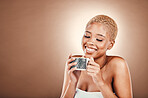 Drinking, smile and black woman with coffee in morning isolated on a brown background in studio. Relax, happy and African girl with a warm drink for comfort, stress relief and happiness with mockup