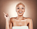 Black woman, portrait and beauty cream with hand pointing at mockup on brown background for dermatology. Happy model smile in studio for skincare, cosmetic and facial glow space for product placement