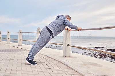 Buy stock photo Senior man, fitness and stretching at beach sidewalk for energy, wellness and healthy cardio workout. Elderly male, warm up and exercise at seaside promenade for training, sports and body performance