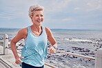 Senior woman, fitness and running at beach promenade, sky mockup and energy for health, wellness and workout. Elderly female, exercise and runner at ocean for happy sports, cardio fitness or marathon