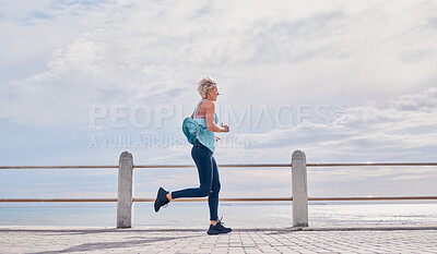 Buy stock photo Senior woman running outdoor at beach promenade, sky mockup and energy for health, wellness and workout. Elderly female, exercise and runner at ocean for sports training, fitness and cardio marathon