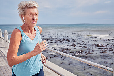 Buy stock photo Senior woman, exercise and running at beach promenade, sky mockup or energy of health, wellness and workout. Elderly female, earphones and fitness at ocean of sports, cardio runner and strong mindset