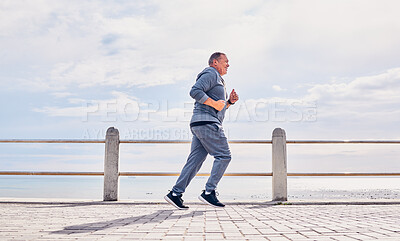 Buy stock photo Senior man running outdoor at beach promenade, sky mockup and energy for body, wellness and cardio workout. Elderly male, exercise and runner at seaside for sports training, fitness or healthy action