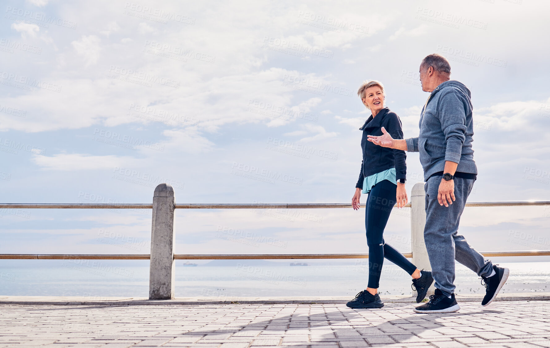 Buy stock photo Walking, fitness and senior couple talking by ocean for exercise, healthy body and wellness in retirement. Sports, nature and elderly man and woman for warm up, cardio workout and training outdoors