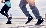 Legs of people, fitness and running at promenade beach for energy, wellness and workout. Closeup man, woman and feet outdoor for cardio exercise at sea for marathon training, shoes and sports runners