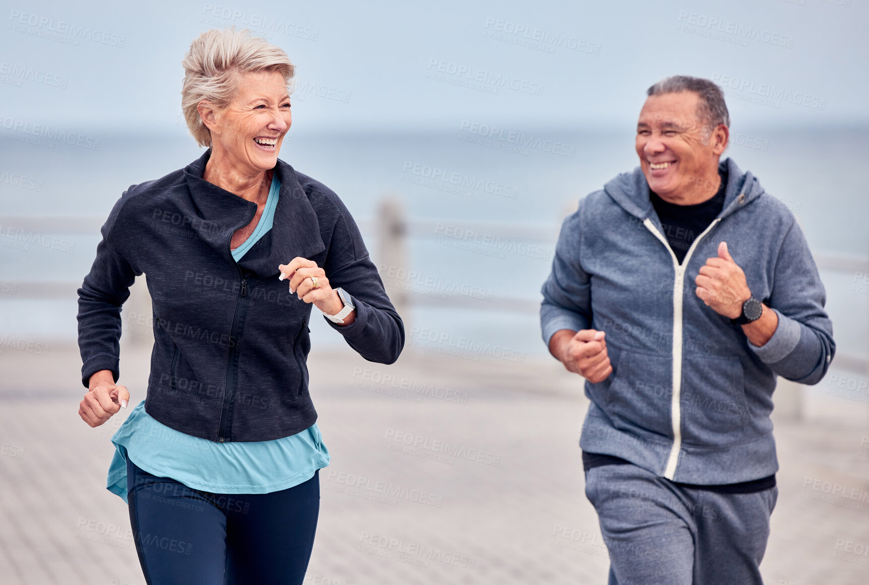 Buy stock photo Fitness, running and happy senior couple by ocean for exercise, healthy body and wellness in retirement. Sports, marriage and elderly man and woman smile for run, cardio workout and training outdoors