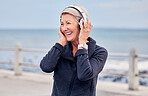 Old woman at beach, headphones and listening to music with smile on face, happiness and freedom outdoor. Fitness, fresh air and technology, podcast or radio streaming with mature female in retirement