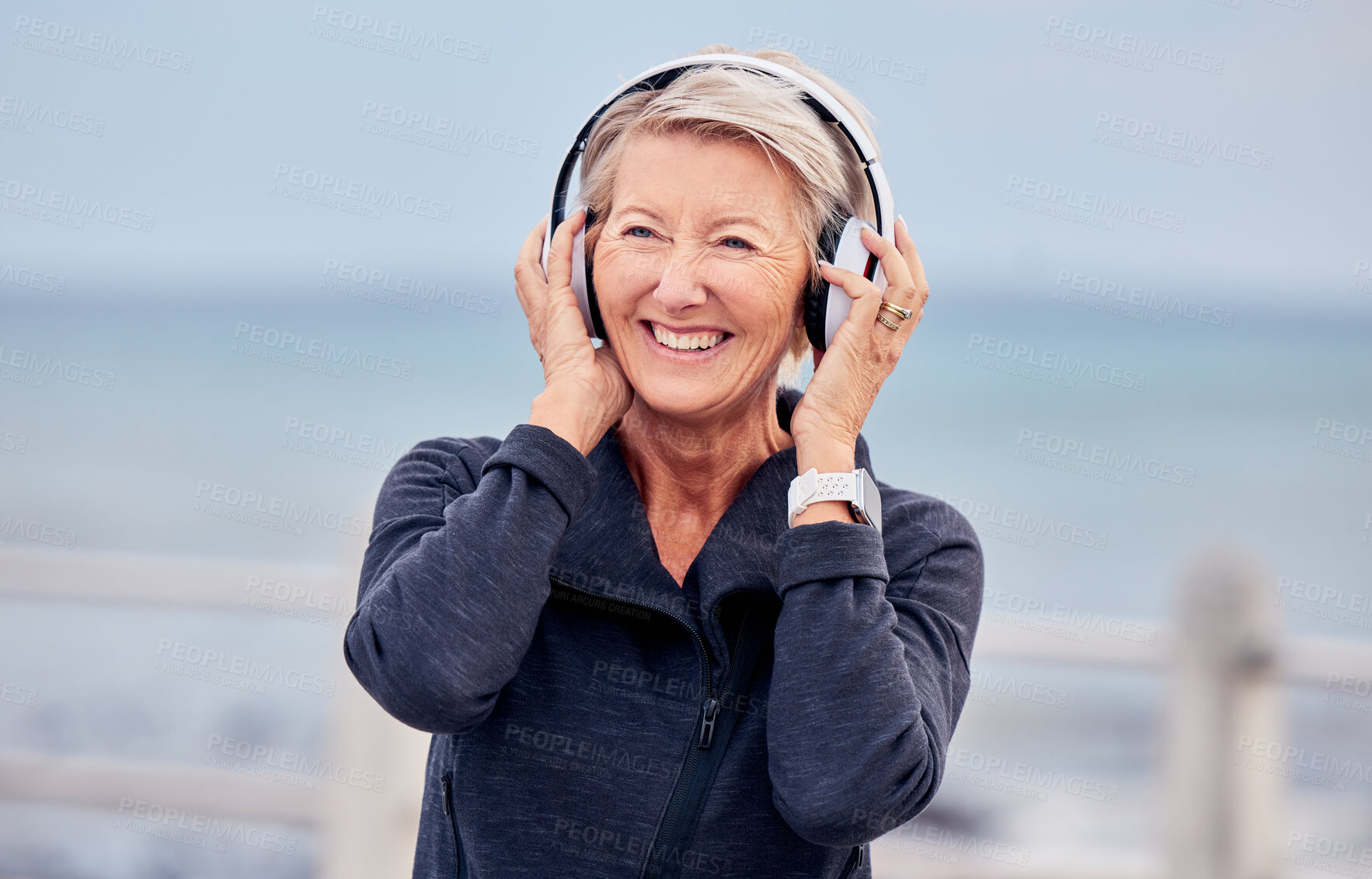 Buy stock photo Old woman at beach, headphones and listen to music with smile on face, happiness and freedom outdoor. Fitness, fresh air and technology, podcast or radio streaming with mature female in retirement