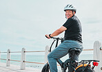 Ebike, portrait and travel with a senior man on the promenade, riding eco friendly transport by the beach. Sustainability, cycling and mock up with a mature male tourist by the seaside for a ride