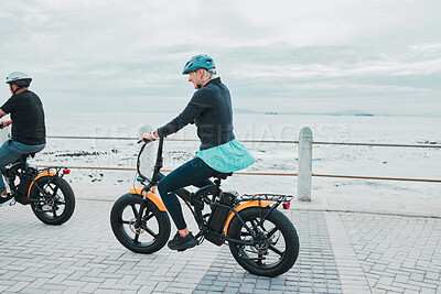 Buy stock photo Couple, helmet or electrical bike by beach, ocean or sea in future transport, clean energy or sustainability travel. Technology, electric or eco friendly bicycle for happy woman or mature cycling man