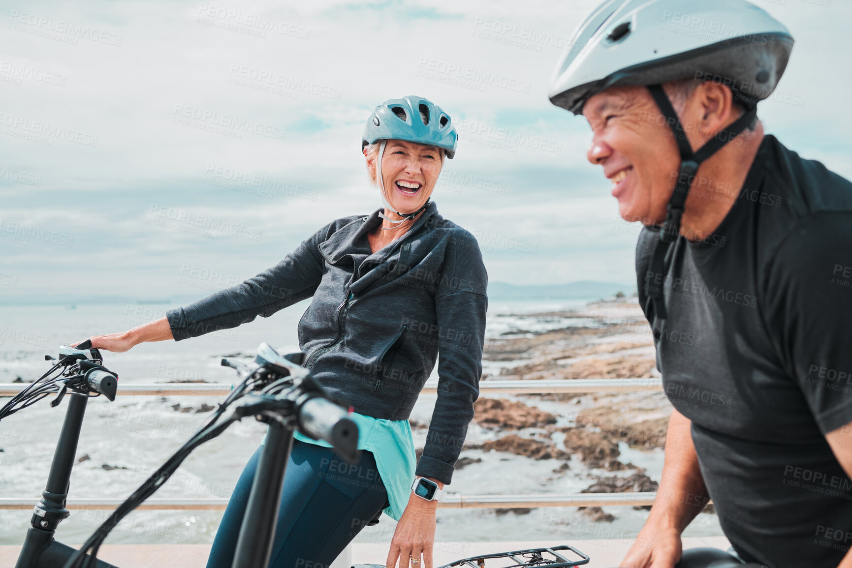 Buy stock photo Laughing couple, helmet or electrical bike by sea in transportation, clean energy or sustainability travel bonding. Technology, electric or eco friendly bicycle for funny woman or mature cycling man