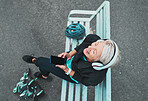 Phone, happy and woman roller skating with music for training, exercise and fun on a city bench. Laughing, mobile and above of a mature lady listening to a podcast while ready to start a skate