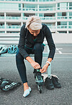 Roller skate, tie shoes and senior woman in city ready for sports, adventure and fitness hobby outdoors. Exercise, holiday and elderly woman tying shoelace from skating, travel and journey in road