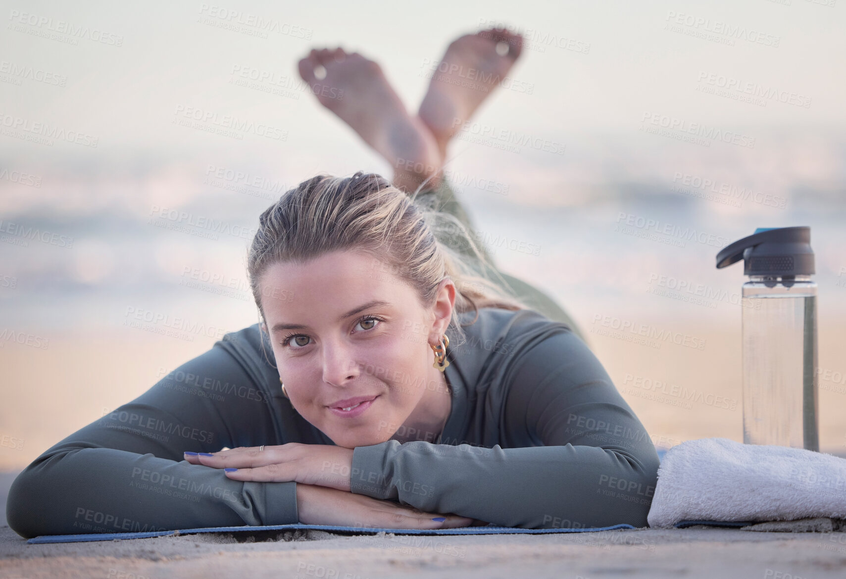 Buy stock photo Woman, portrait and relaxing on beach for yoga, exercise or spiritual wellness lying on mat with bottle and towel. Happy female relax in fitness with smile for zen workout, training or mental health