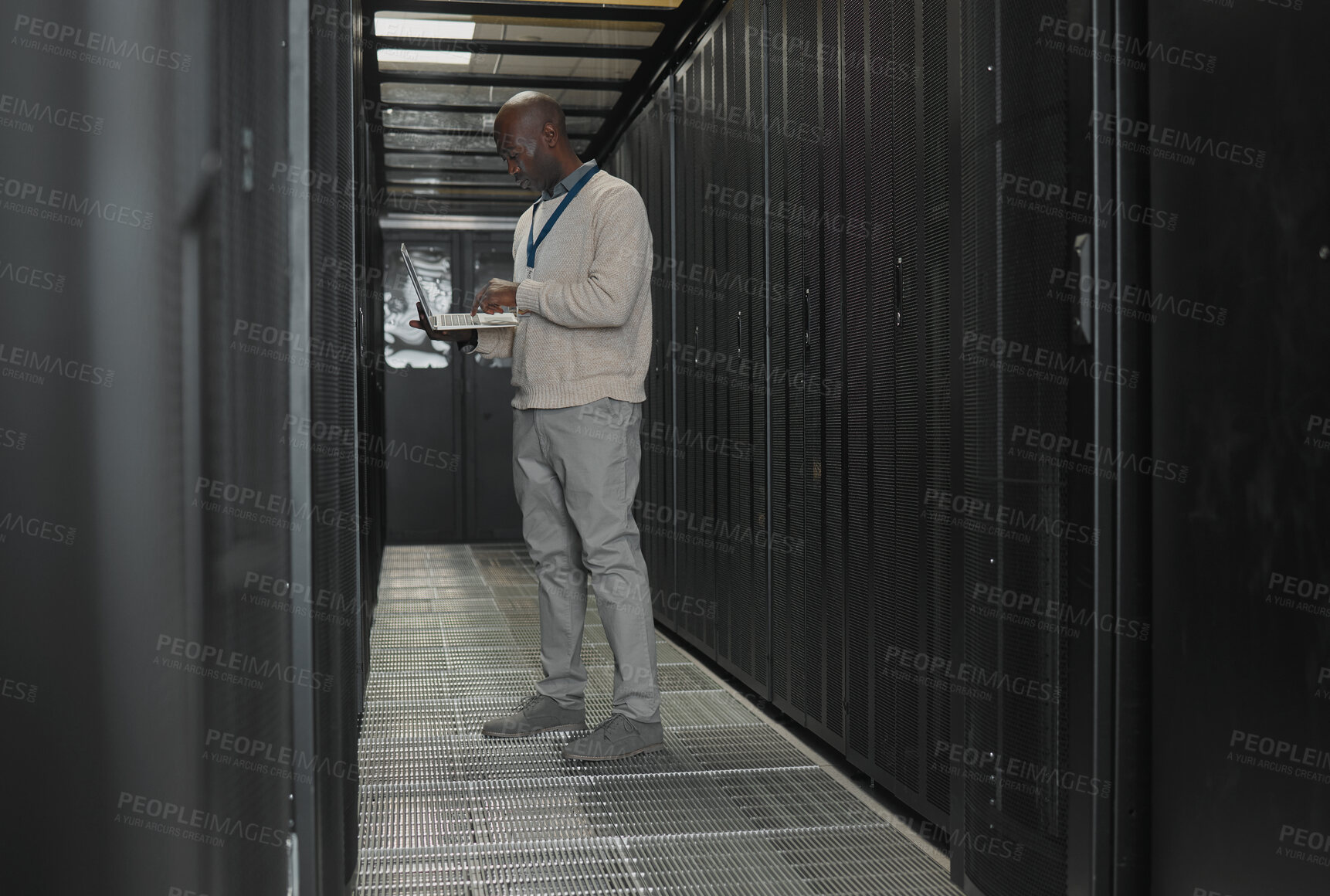 Buy stock photo Server room, data center or IT black man with laptop for research, engineer working in  dark server room. Computer, cybersecurity and analytics with male programmer problem solving or troubleshooting