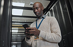 Phone, search or IT black man in data center for research, communication or typing in dark server room. Serious, focus or male with smartphone for networking, social media or reading website content