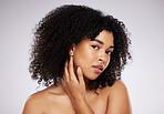 Skincare, looking and portrait of a black woman feeling face isolated on a grey studio background. Beauty, African and model touching skin to check for acne, grooming and routine on a backdrop