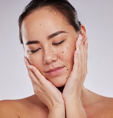 Buy stock photo Beauty, face and skincare of woman in studio for cosmetics, dermatology and glow. Aesthetic asian model person with hands on skin for makeup, mole and facial self care for wellness on grey background