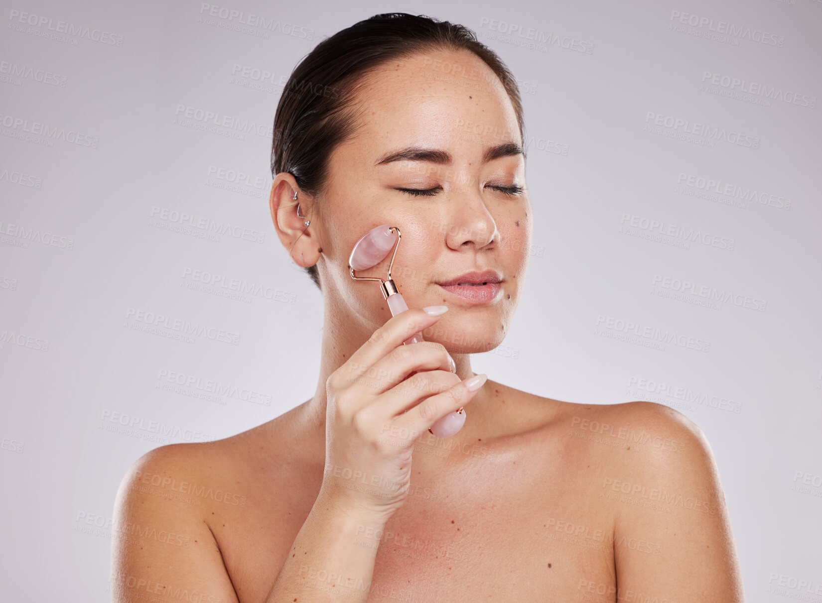 Buy stock photo Face skincare, eyes closed and woman with jade roller in studio isolated on a gray background. Beauty cosmetics, dermatology and young female model with rose quartz stone or product for healthy skin