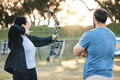 Buy stock photo Archery, sports or help with a woman holding a bow and arrow outdoor for target practice with a coach. Coaching, learning or advice with a female and trainer at the shooting range for weapon training