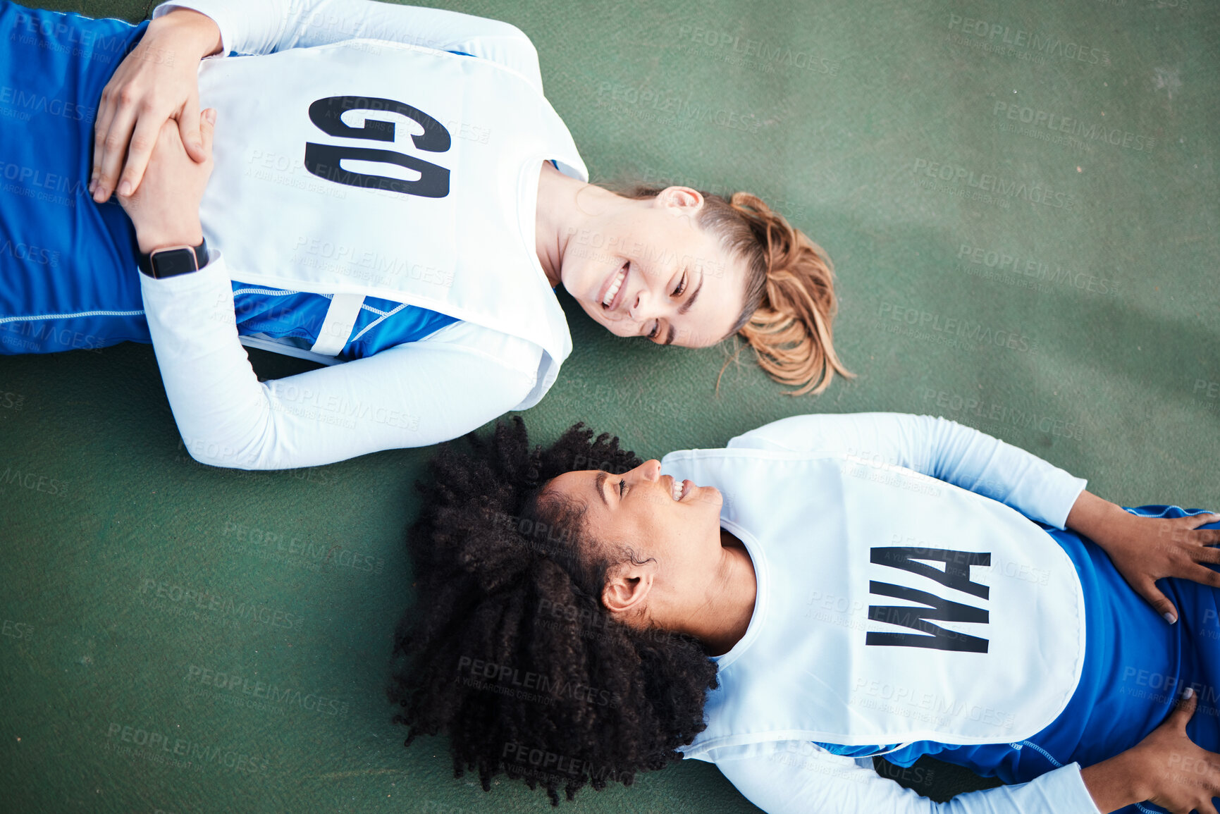 Buy stock photo Exercise, netball and women on ground, fitness and training for wellness, healthy lifestyle and smile. Rest, female athlete and players on court, relax and break after practice, happiness and winning