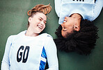 Friends, sports and overhead with women lying on the ground at a court to relax after training. Fitness, team or smile with a happy female athlete and friend resting together while finished exercise