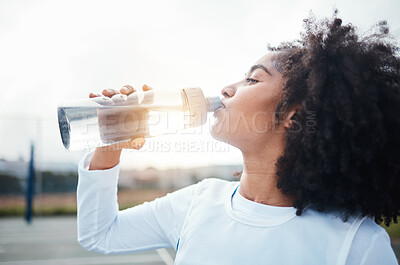 Buy stock photo Black woman, sports and drinking water at court during training, workout and sport exercise outdoors. Fitness, thirsty and girl with bottle for wellness, hydration and recovery during practice