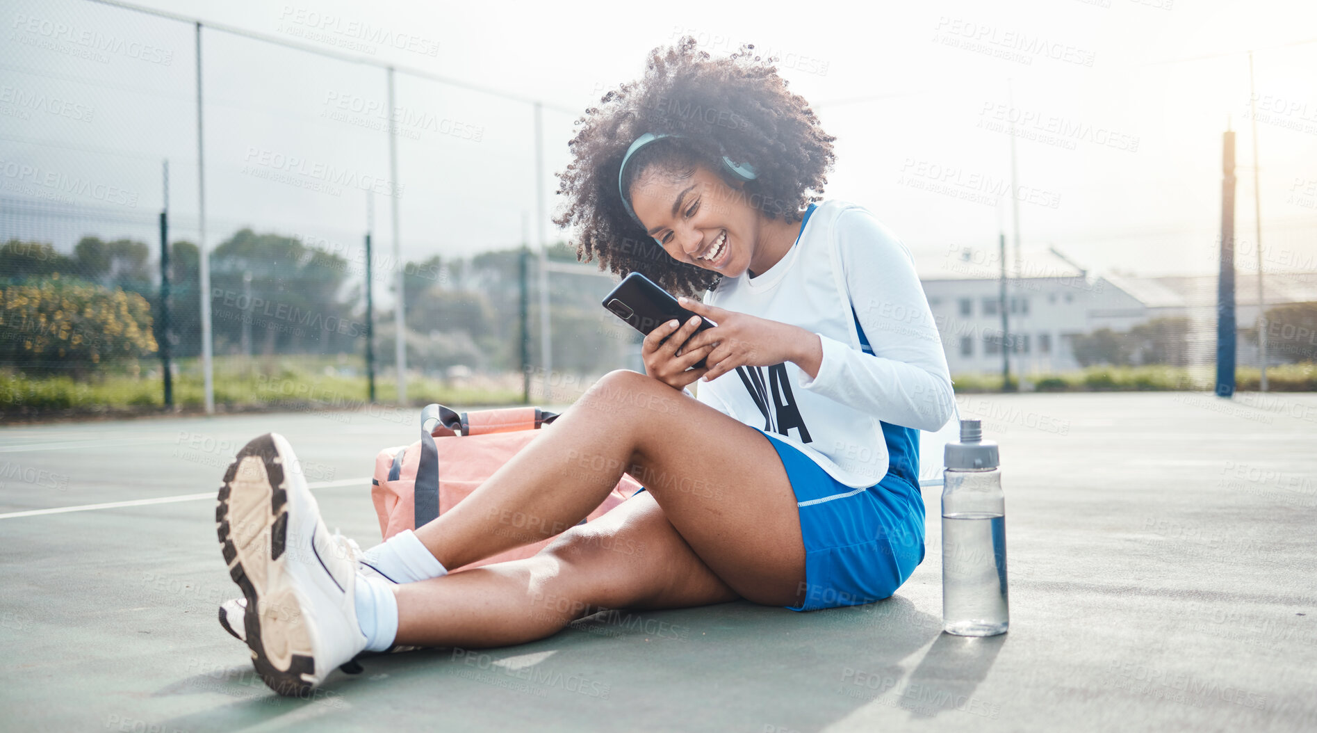 Buy stock photo Netball sports, phone music and athlete listening to mp3 radio, audio podcast or song after training workout. Laughing on court, online digital headphones and black woman streaming funny meme video
