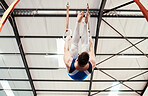 Man, acrobat and gymnastics turning on rings in fitness for practice, training or workout at gym. Professional male gymnast hanging on ring circles for athletics, acrobatics or strength exercise