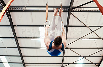 Buy stock photo Man, acrobat and gymnastics hanging on rings in fitness for practice, training or workout at gym. Professional male gymnast on ring circles below for athletics, acrobatics or strength exercise
