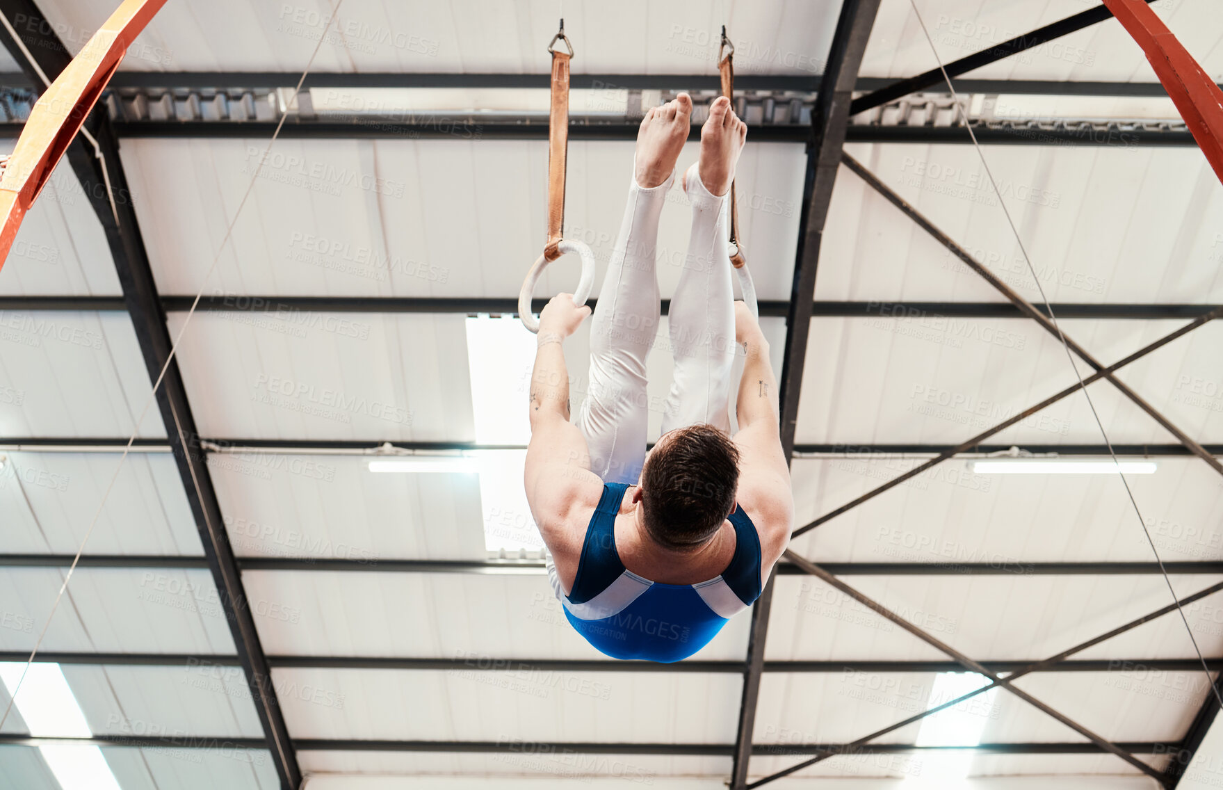 Buy stock photo Man, acrobat and gymnastics hanging on rings in fitness for practice, training or workout at gym. Professional male gymnast on ring circles below for athletics, acrobatics or strength exercise