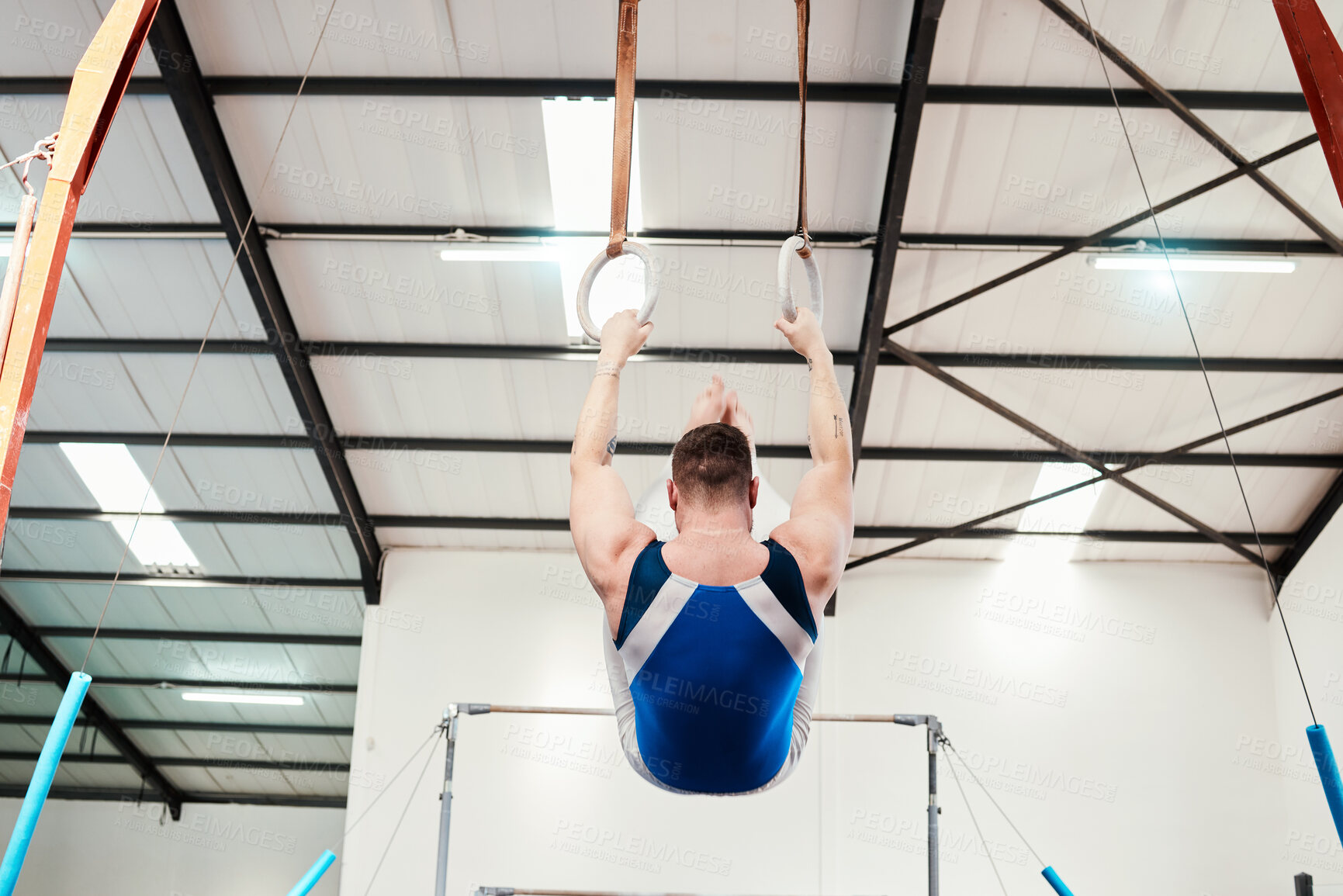 Buy stock photo Man, acrobat and gymnast swinging on rings in fitness for practice, training or workout at gym. Professional male in gymnastics hanging on ring circles for athletics, acrobatics or strength exercise