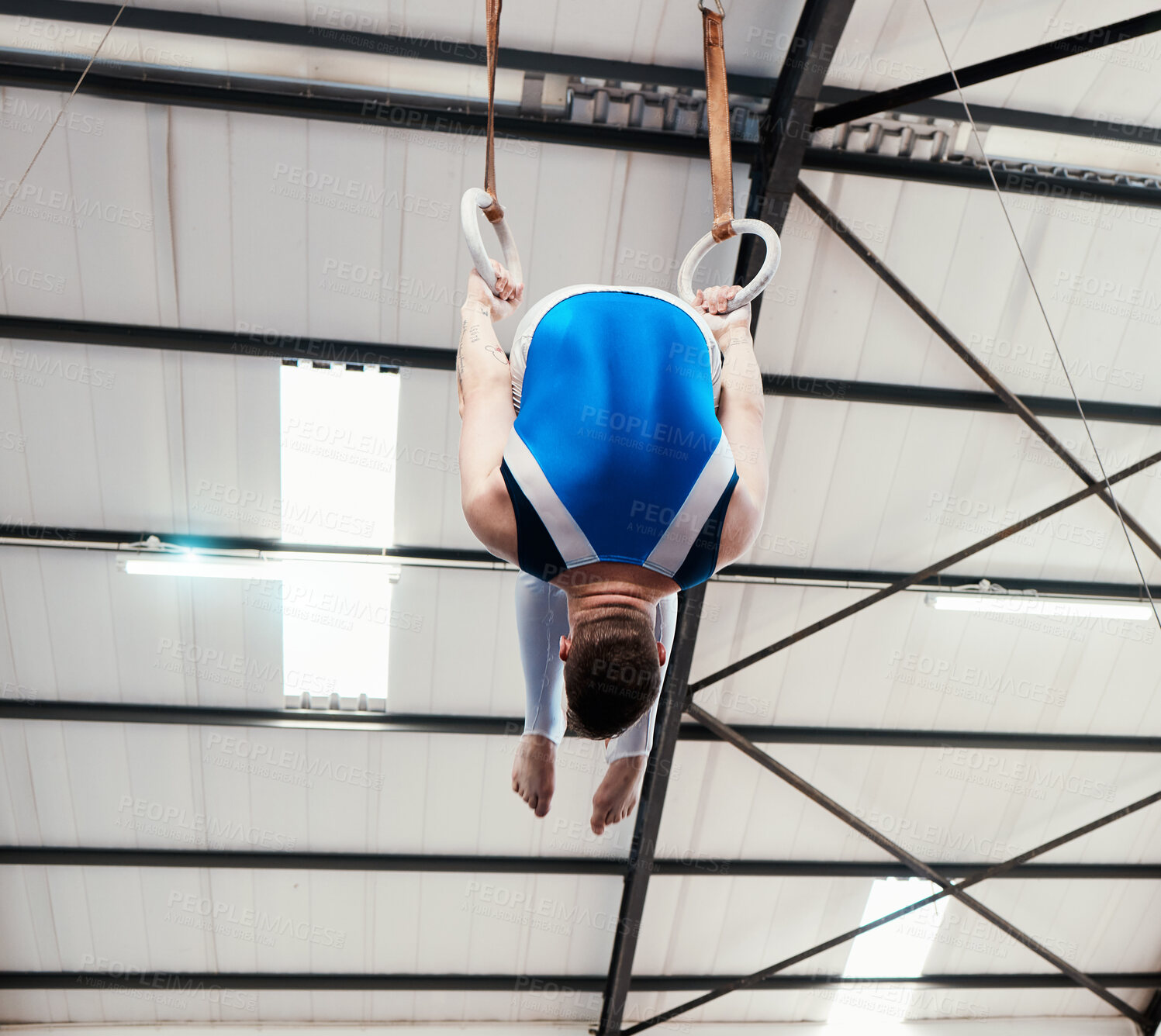 Buy stock photo Man, acrobat and gymnast turning on rings in fitness for practice, training or workout at gym. Professional male gymnastics hanging on ring circles for athletics, balance or strength exercise indoors