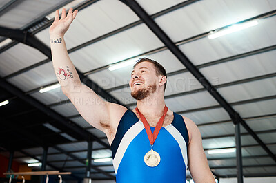 Man, medal celebration and winning smile with wave, sports and hand in air at competition with pride. Champion athlete, happy and winner with gold, celebrate or success in global gymnastics contest