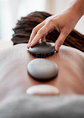 Buy stock photo Black woman, hands and rock on back in spa treatment for relaxation, stress relief or massage at resort. Hand of masseuse applying rocks to African American female in physical therapy for wellness