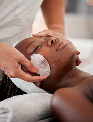 Buy stock photo Black woman face, relax and gua sha stone spa treatment of a young female with facial. Skincare, beauty and wellness clinic with client feeling calm and zen from massage and dermatology glow