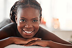 Spa, portrait and black woman with smile, massage and salon luxury treatment, bare and lying on table. Face, African American female and lady with happiness, relax and healing therapy for wellness